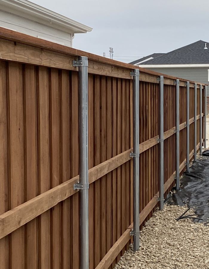 Tall cedar screen wall built on galvanized steel posts at a commercial site