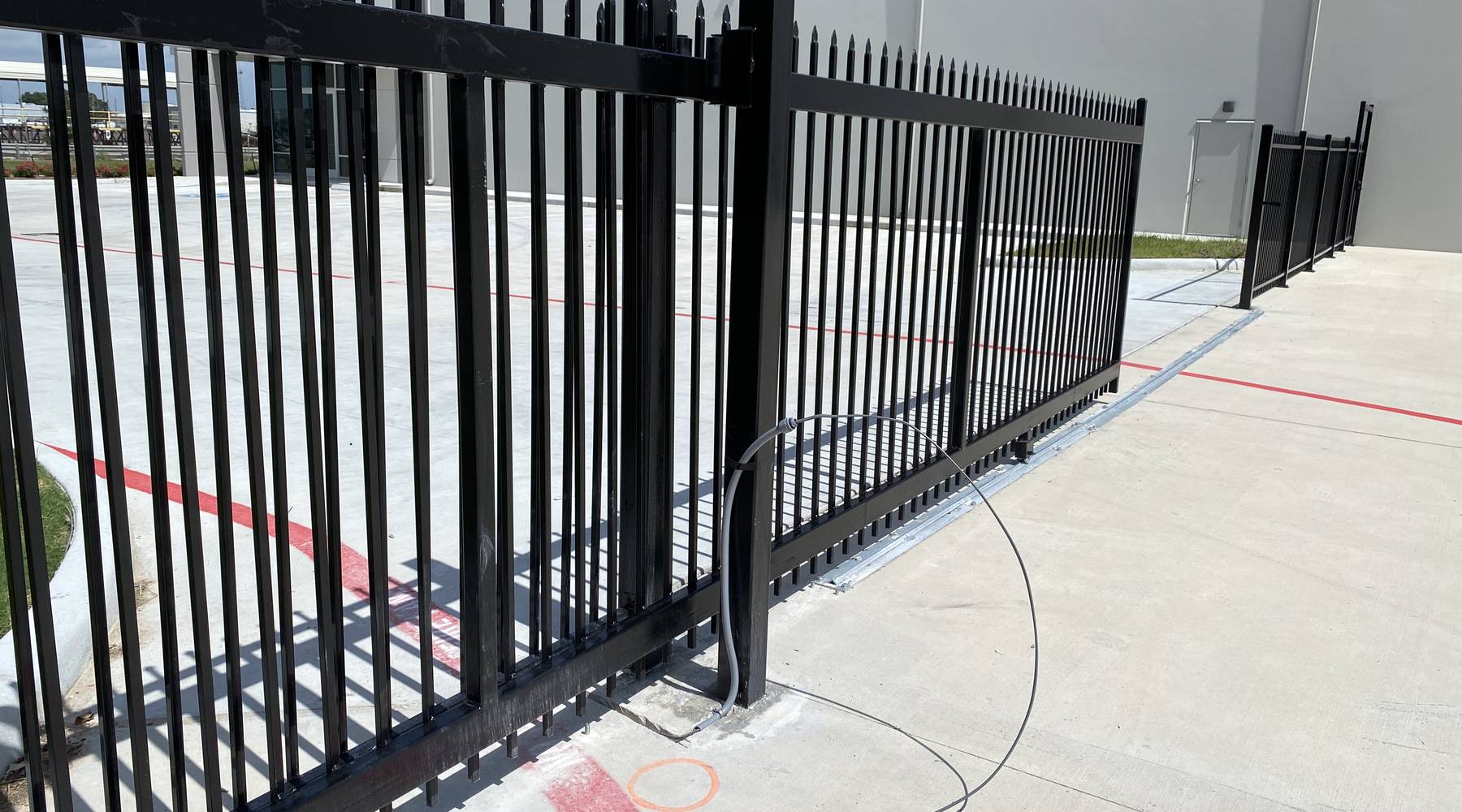 Tall black ornamental iron fence running along a commercial parking lot