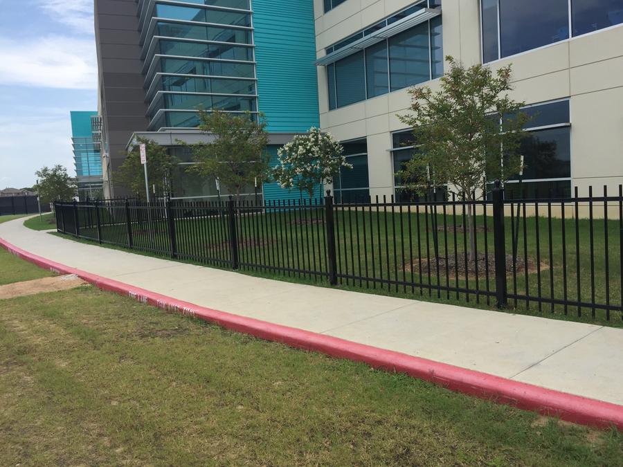 Black iron fence along a modern corporate campus walkway
