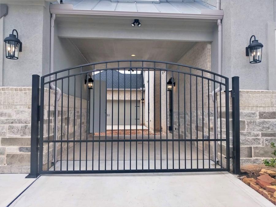 Arched black iron pedestrian gate in a stone entry