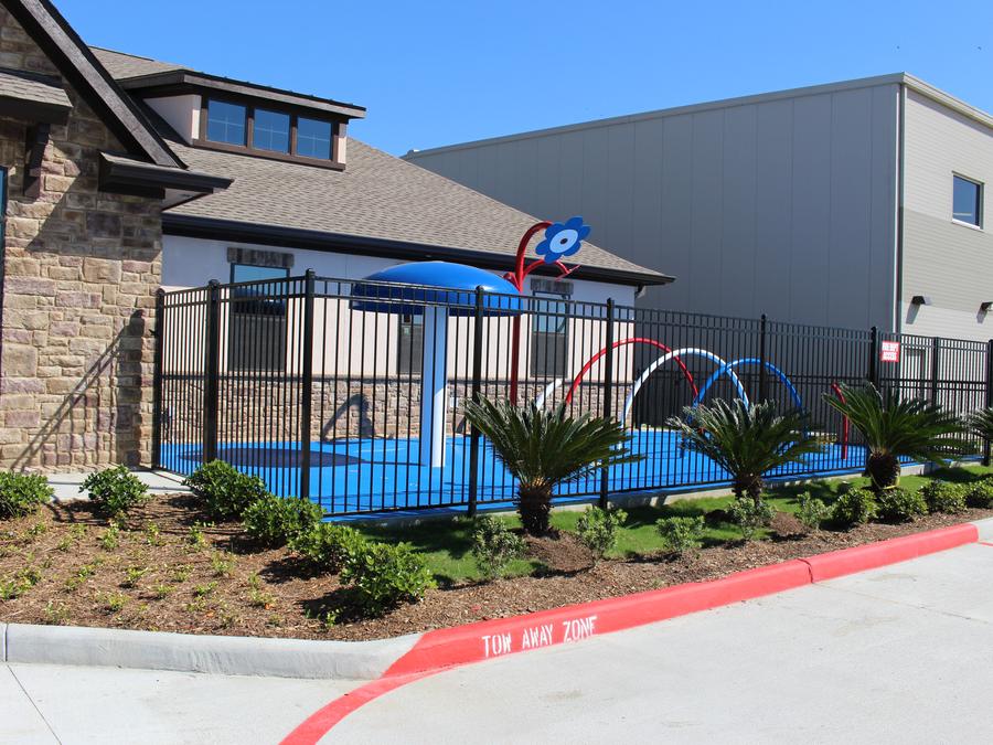 Iron fence enclosing a school splash pad and play area