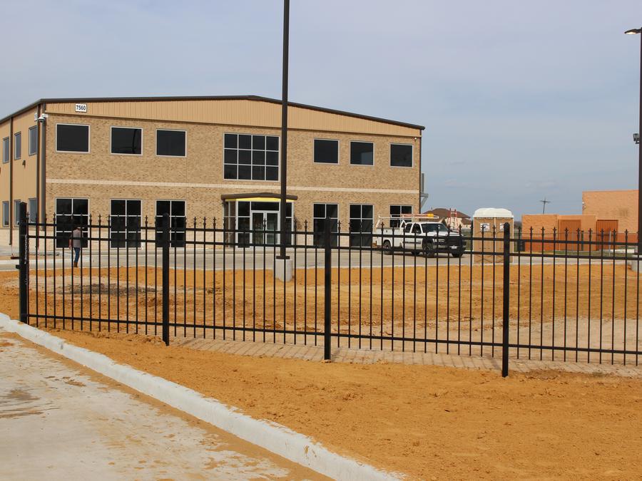 Iron perimeter fence around a graded commercial lot and office building