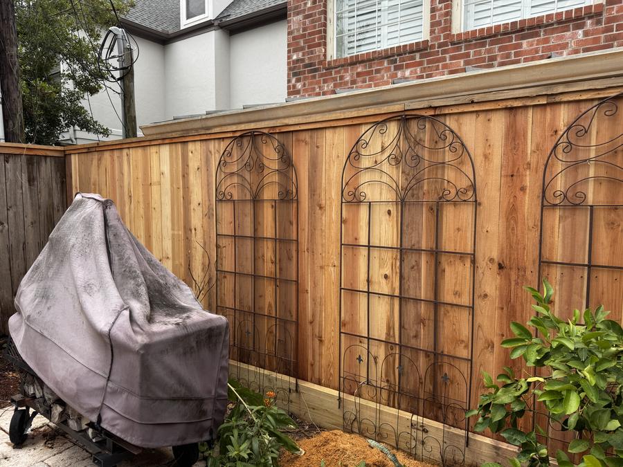Cedar fence with decorative arched ironwork panels set into it