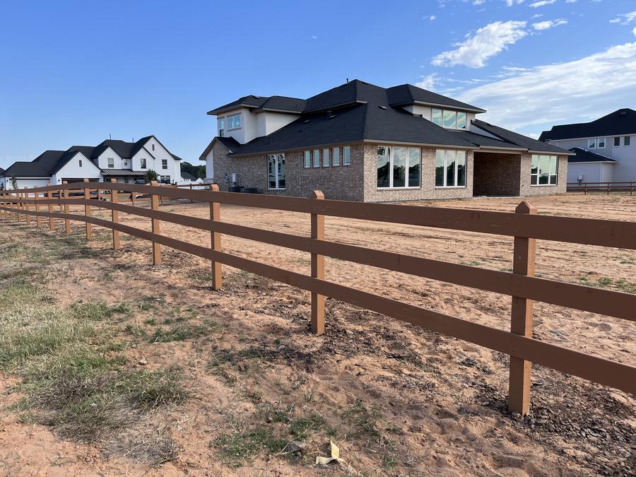 Three-rail ranch fence running along a new home community