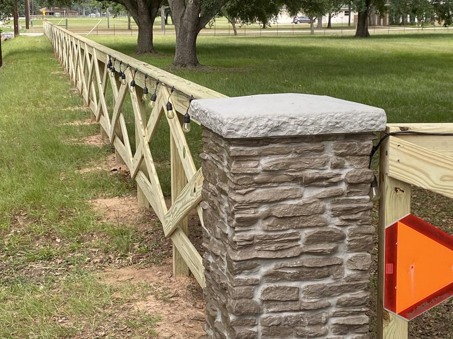 Stone column with cross-buck rail fence at a property entrance