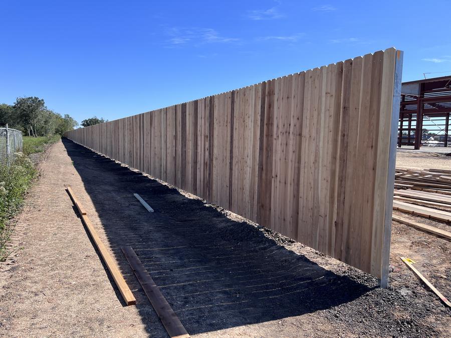 Long run of tall cedar privacy fence disappearing to a vanishing point