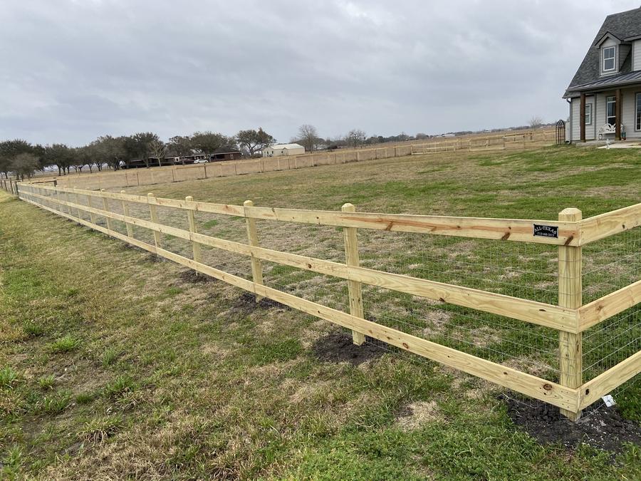 Wood rail and wire pasture fence crossing an open field