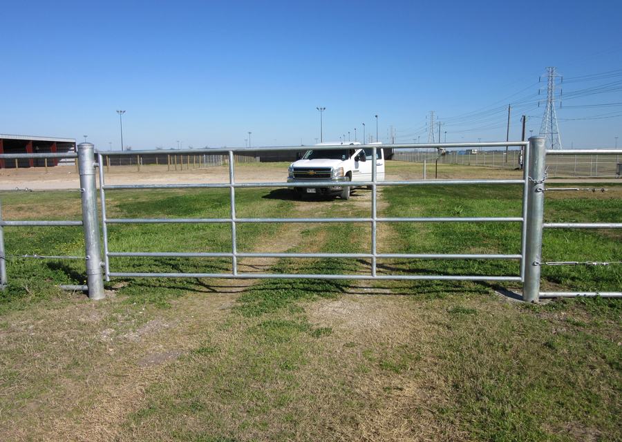 Galvanized pipe framework and drive gate on an open commercial lot