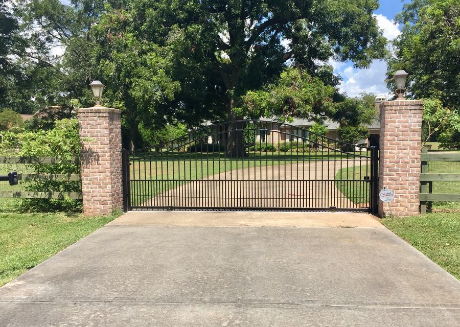 Iron drive gate between stone columns with an automatic operator